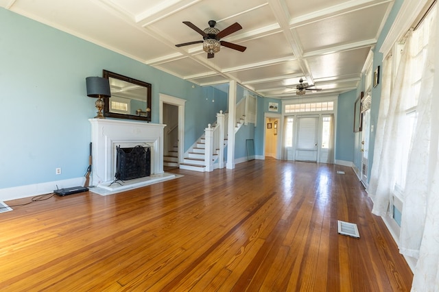 unfurnished living room featuring beam ceiling, ceiling fan, coffered ceiling, hardwood / wood-style flooring, and ornamental molding