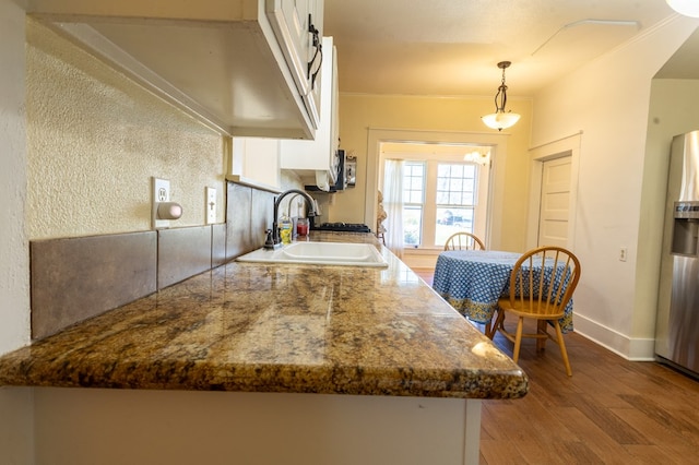 kitchen featuring sink, white cabinets, pendant lighting, and hardwood / wood-style flooring