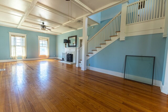 unfurnished living room with beam ceiling, ceiling fan, wood-type flooring, and coffered ceiling