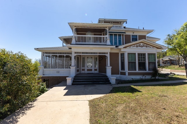 view of front facade with a balcony, covered porch, and a front yard