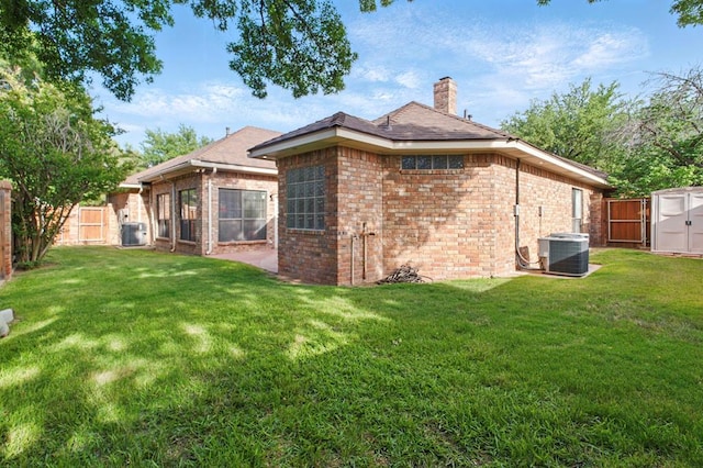 back of house with brick siding, central AC, a chimney, and a storage shed