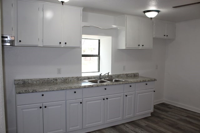 kitchen with sink, a textured ceiling, dark hardwood / wood-style floors, light stone countertops, and white cabinets