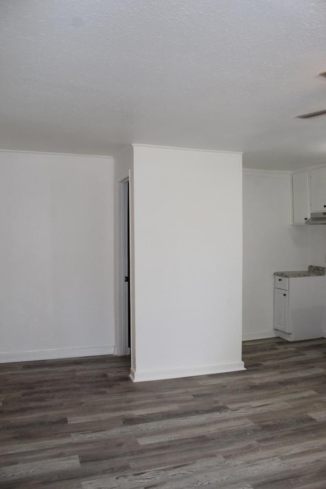 empty room with ornamental molding, a textured ceiling, and dark hardwood / wood-style flooring