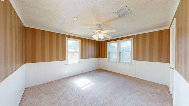 carpeted spare room featuring ceiling fan, crown molding, and a textured ceiling