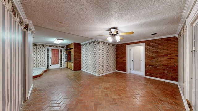 spare room with a textured ceiling, ceiling fan, ornamental molding, and brick wall