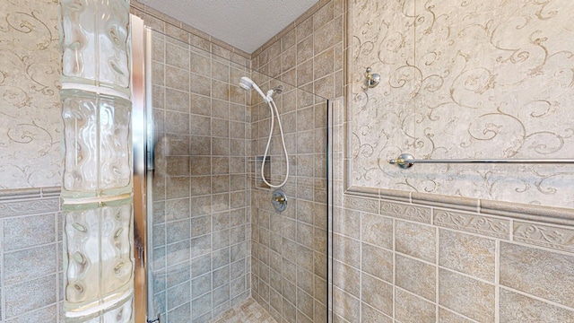 bathroom featuring tiled shower, a textured ceiling, and tile walls