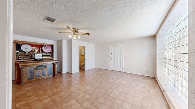 unfurnished living room with a textured ceiling and ceiling fan