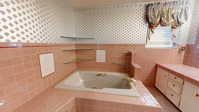 bathroom featuring vanity, a textured ceiling, tiled bath, and tile walls