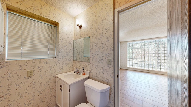 bathroom with tile patterned flooring, vanity, toilet, and a textured ceiling