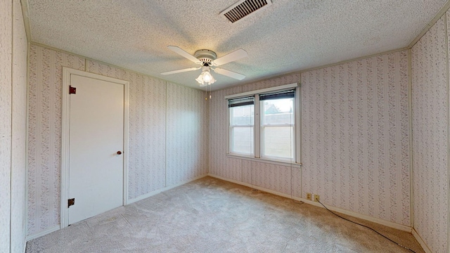 unfurnished room with a textured ceiling, ceiling fan, and light carpet