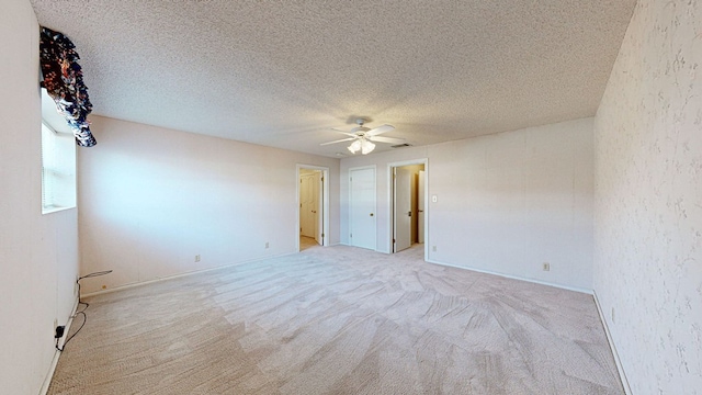 empty room with ceiling fan, light colored carpet, and a textured ceiling