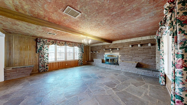 unfurnished living room featuring wood walls, beamed ceiling, and an inviting chandelier