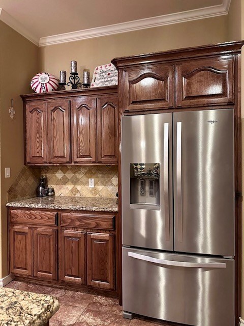 3113 San Pedro Dr, Odessa, TX 79765 - kitchen featuring stainless steel refrigerator with ice dispenser, crown molding, decorative backsplash, and light stone counters