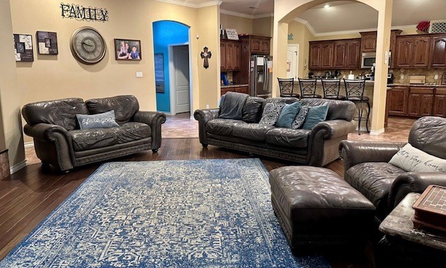 3113 San Pedro Dr, Odessa, TX 79765 - living room featuring arched walkways, crown molding, and dark wood-type flooring