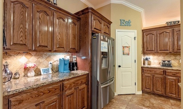 3113 San Pedro Dr, Odessa, TX 79765 - kitchen featuring stainless steel refrigerator with ice dispenser, ornamental molding, light stone countertops, tasteful backsplash, and brown cabinetry