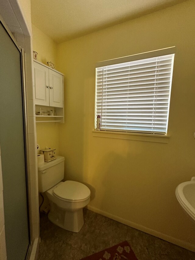 bathroom featuring tile patterned flooring, toilet, and walk in shower