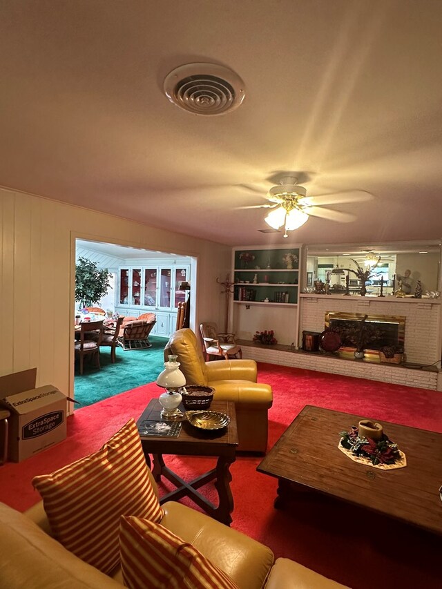 living room with ceiling fan, carpet floors, and a brick fireplace