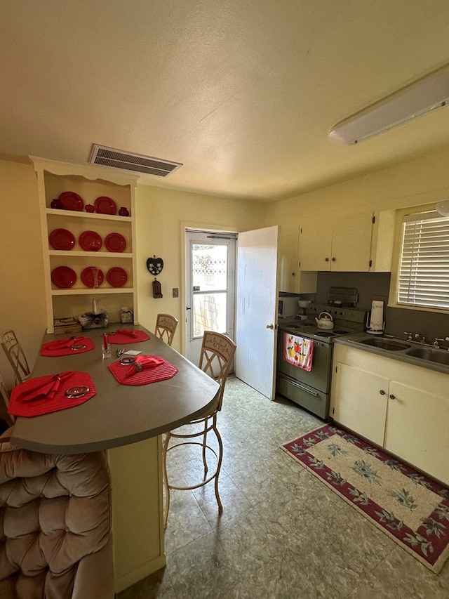 kitchen with a kitchen breakfast bar, electric range oven, kitchen peninsula, and sink