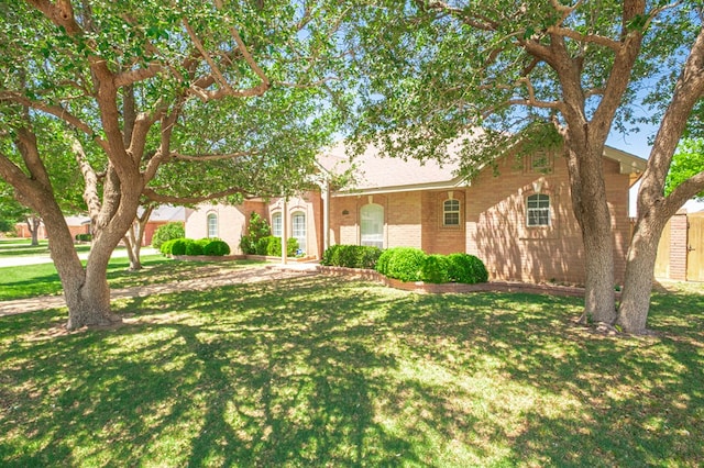 view of front facade with brick siding and a front yard