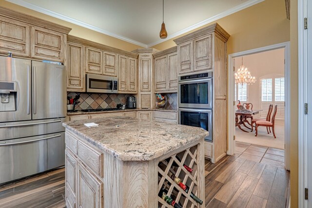 kitchen featuring appliances with stainless steel finishes, tasteful backsplash, light stone counters, a chandelier, and ornamental molding