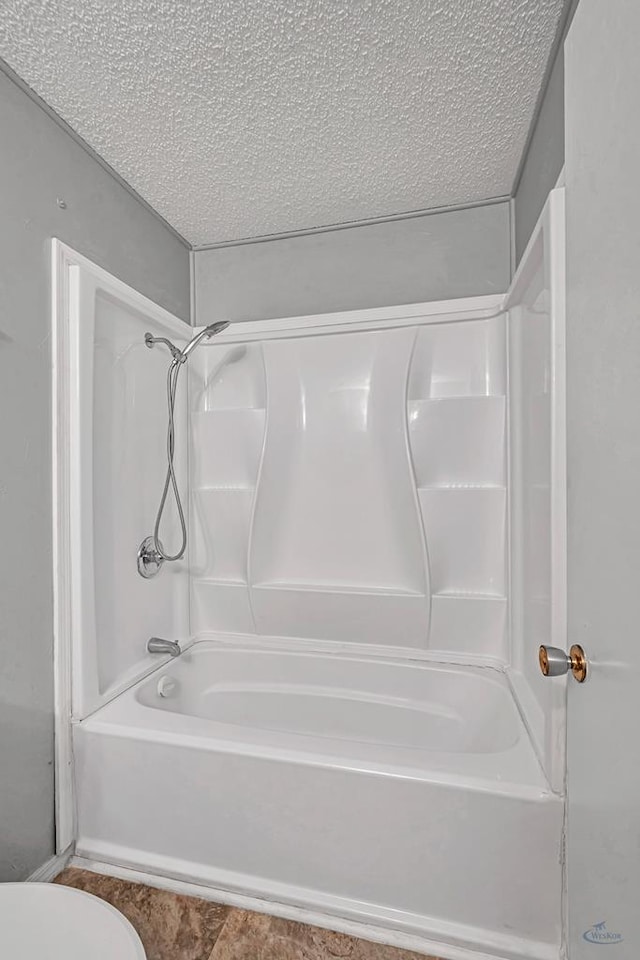 bathroom featuring a textured ceiling,  shower combination, and toilet