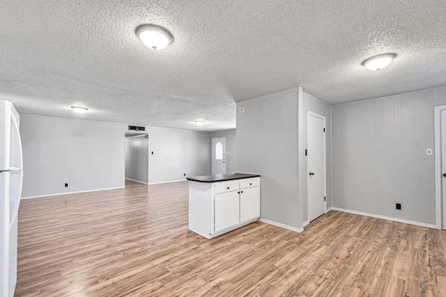 interior space featuring white fridge, a textured ceiling, and light hardwood / wood-style flooring