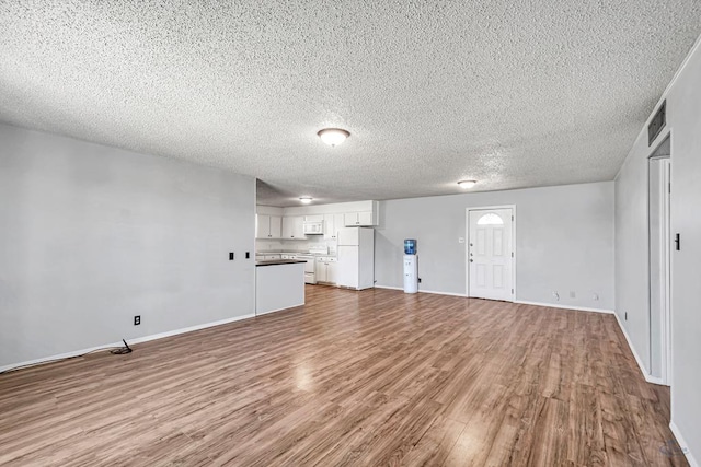 unfurnished living room featuring a textured ceiling and light wood-type flooring