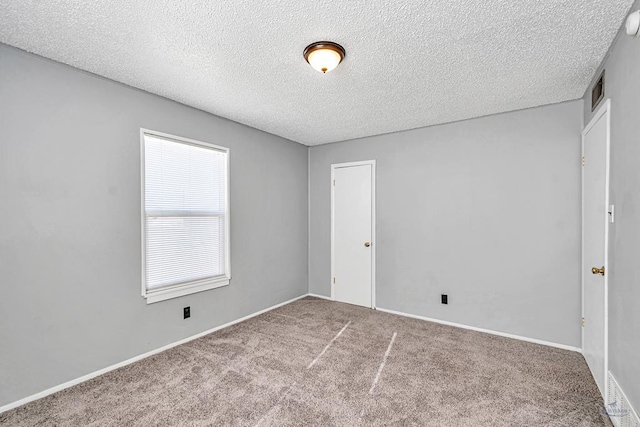 carpeted empty room featuring a textured ceiling