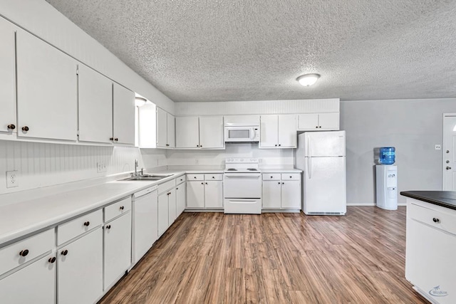 kitchen with white cabinetry, sink, wood-type flooring, and white appliances