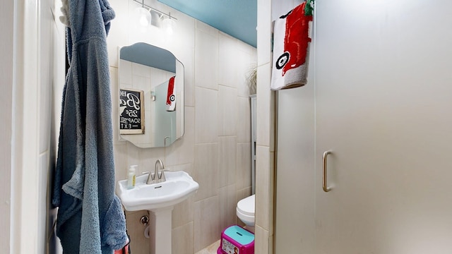 bathroom with toilet, tile walls, and a shower stall