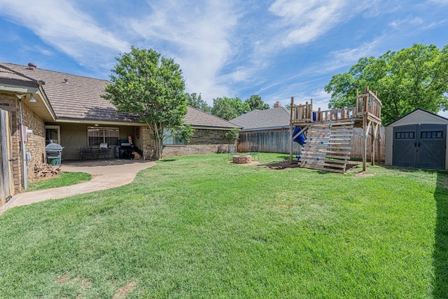 view of yard featuring a storage shed, an outbuilding, a patio, stairs, and an outdoor fire pit