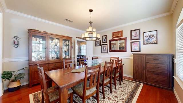 dining room featuring a chandelier, dark wood finished floors, ornamental molding, and baseboards