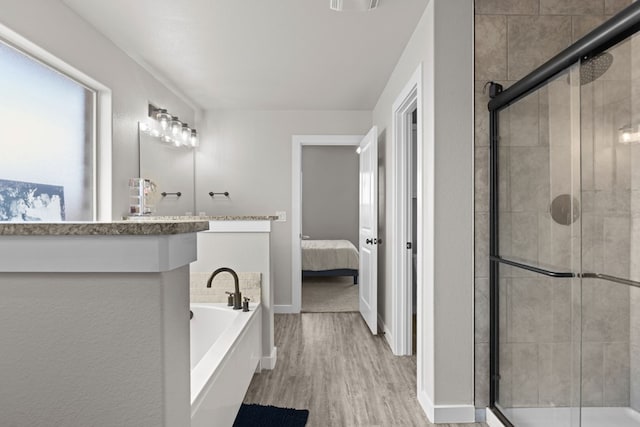 2602 Ivy Ln, Midland, TX 79705 - ensuite bathroom featuring a bath, wood finished floors, a stall shower, and vanity
