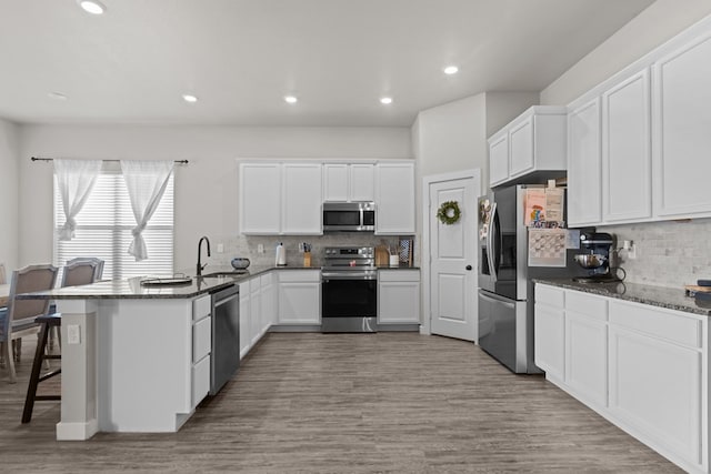 2602 Ivy Ln, Midland, TX 79705 - kitchen featuring stainless steel appliances, a peninsula, white cabinetry, decorative backsplash, and a kitchen bar