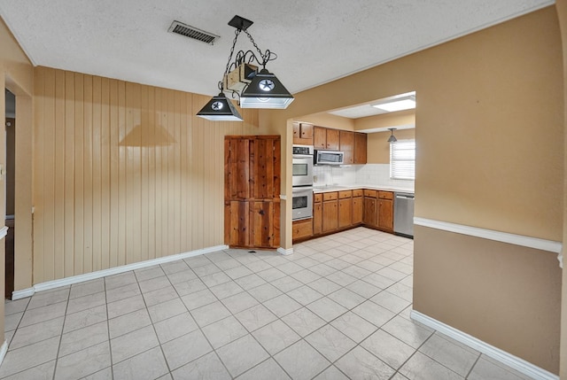 4205 Irvin Dr, Midland, TX 79705 - kitchen with stainless steel appliances, light countertops, brown cabinets, pendant lighting, and decorative backsplash