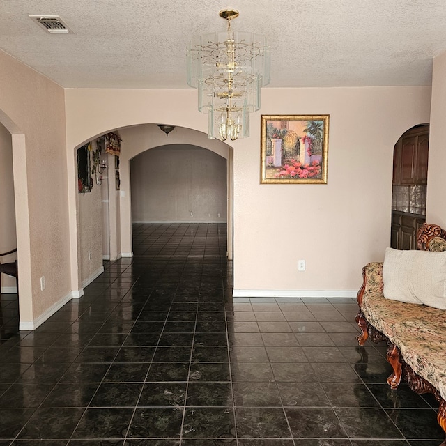 tiled dining room featuring arched walkways, a textured ceiling, visible vents, and a notable chandelier