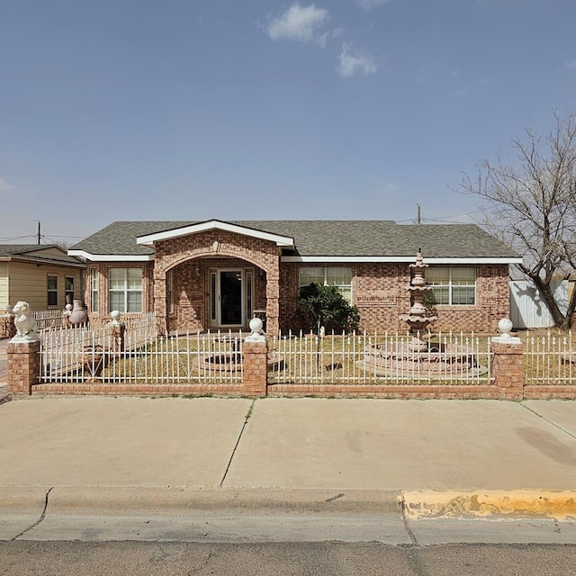 ranch-style house featuring brick siding, a fenced front yard, and a shingled roof