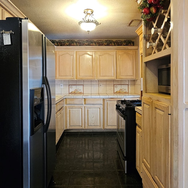 kitchen featuring tile countertops, light brown cabinets, stainless steel appliances, dark tile patterned flooring, and tasteful backsplash