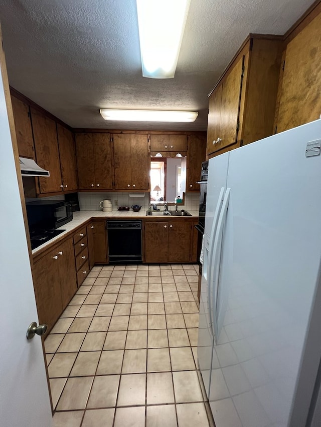 kitchen featuring black appliances, light tile patterned floors, sink, and a textured ceiling