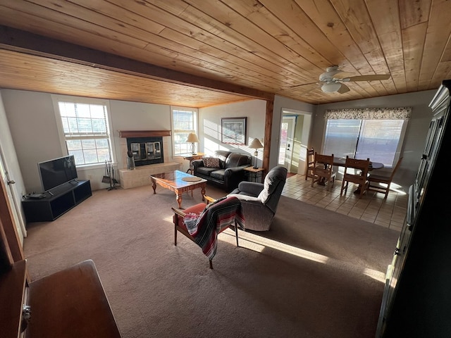 carpeted living room featuring a tile fireplace, vaulted ceiling with beams, ceiling fan, and wooden ceiling