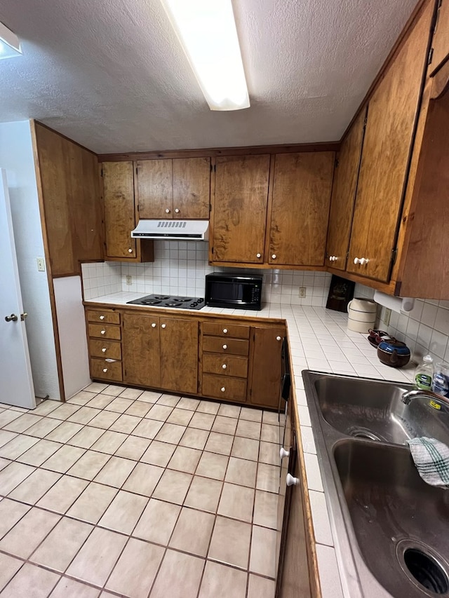 kitchen featuring backsplash, sink, a textured ceiling, tile counters, and electric stovetop