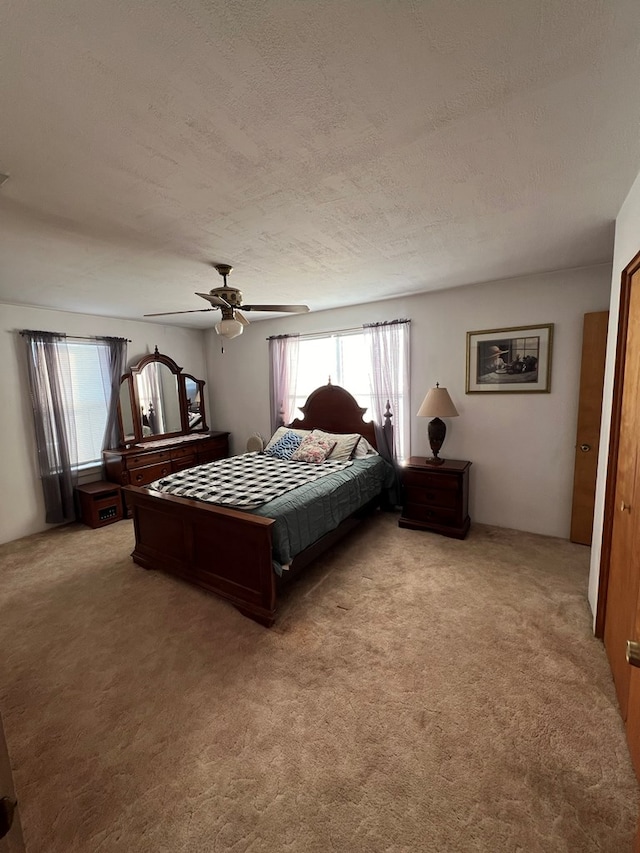 bedroom featuring ceiling fan, light carpet, and a textured ceiling