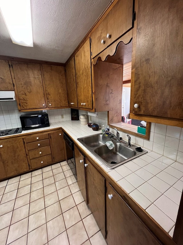 kitchen featuring tile countertops, backsplash, black appliances, ventilation hood, and sink