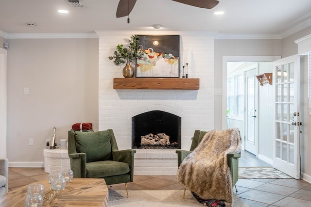 living area featuring a ceiling fan, crown molding, a fireplace, tile patterned floors, and baseboards