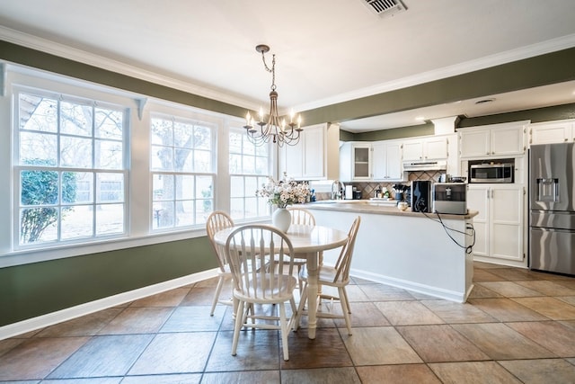 dining area featuring a chandelier, healthy amount of natural light, ornamental molding, and baseboards