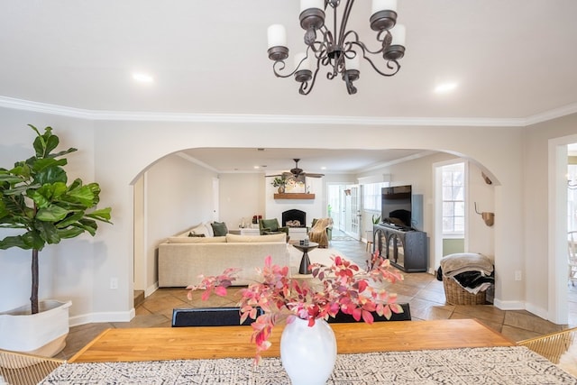 dining room with arched walkways, a fireplace, crown molding, tile patterned floors, and ceiling fan