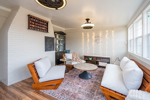 living room with wood finished floors and brick wall
