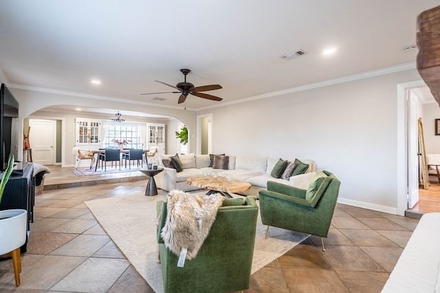 living room featuring arched walkways, a ceiling fan, ornamental molding, baseboards, and stone tile floors