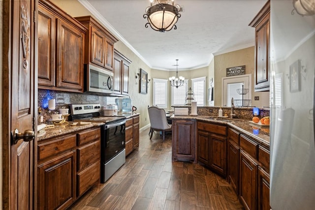 kitchen featuring sink, hanging light fixtures, ornamental molding, stainless steel appliances, and an inviting chandelier