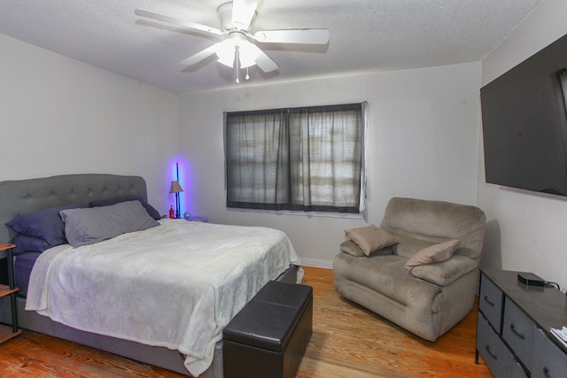 bedroom with a textured ceiling, ceiling fan, and light wood finished floors